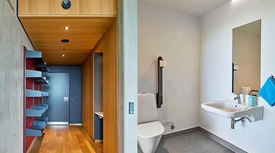 Venstre side af billedet viser lejlighedens entré med opbevaring, køleskab og vask. Højre side viser lejlighedens badeværelse med tilgængeligt toilet, håndvask og spejl.
