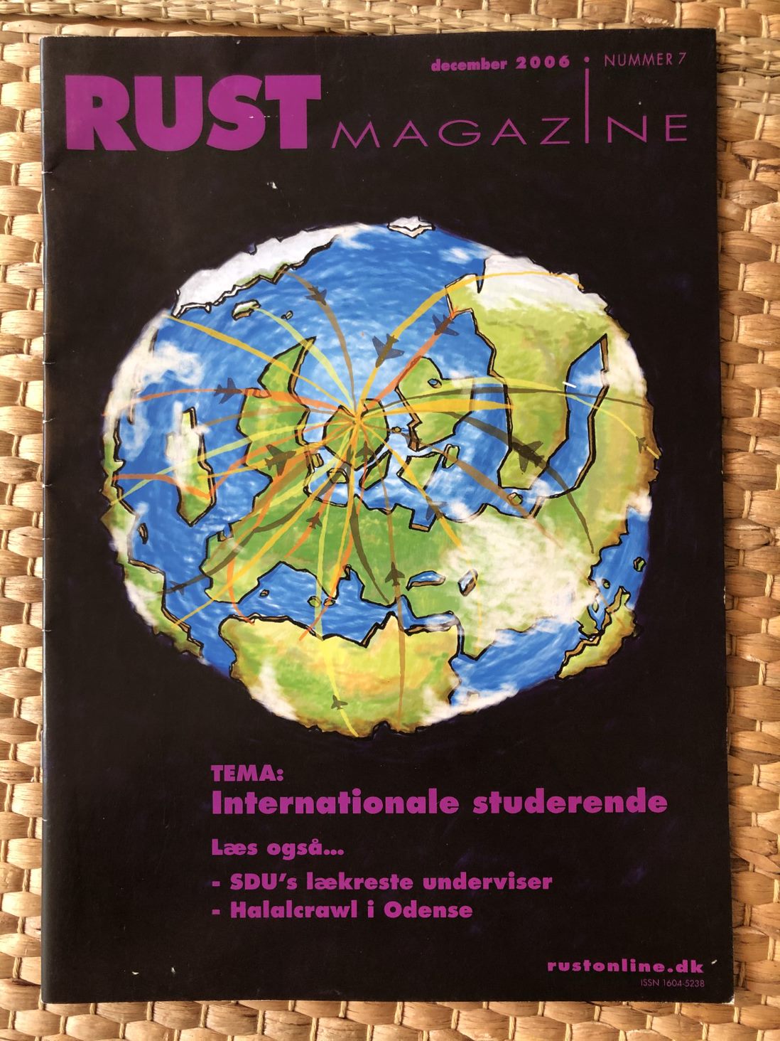 Forside af "RUST MAGAZINE" med en illustreret globus på sort baggrund og temaet "Internationale studerende".